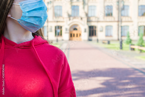 Cropped close up photo portrait of young girl in casual red jumper wearing surgical medicine mask going to hospital