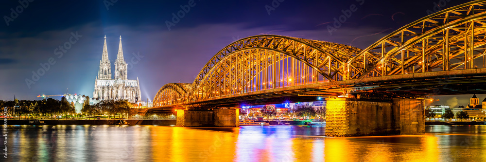 Obraz premium Panorama of the Hohenzollern Bridge over the Rhine River and Cologne Cathedral by night 