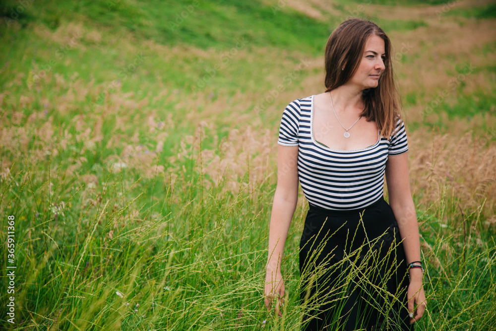 Beautiful girl in a black long skirt and striped T-shirt walks in green hole Beautiful girl in a black long skirt and striped T-shirt walks in green hole