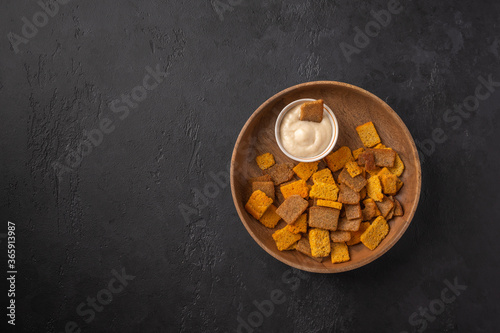 Top view plate with a set of croutons with spices and horseradish on a dark graphite background. Popular appetizer for beer and kvass. Copy space
