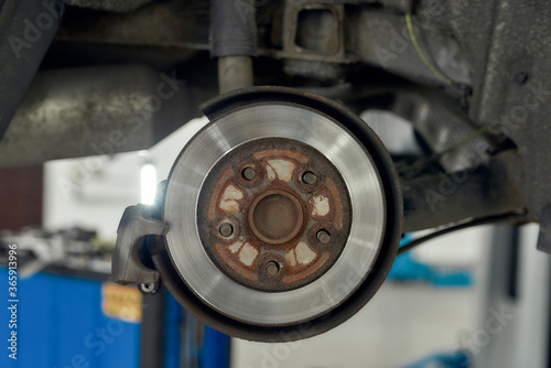 For better performance of a car. Close up of braking disc of the vehicle with brake caliper for repair in process of new tire replacement. Car brake repairing at service station