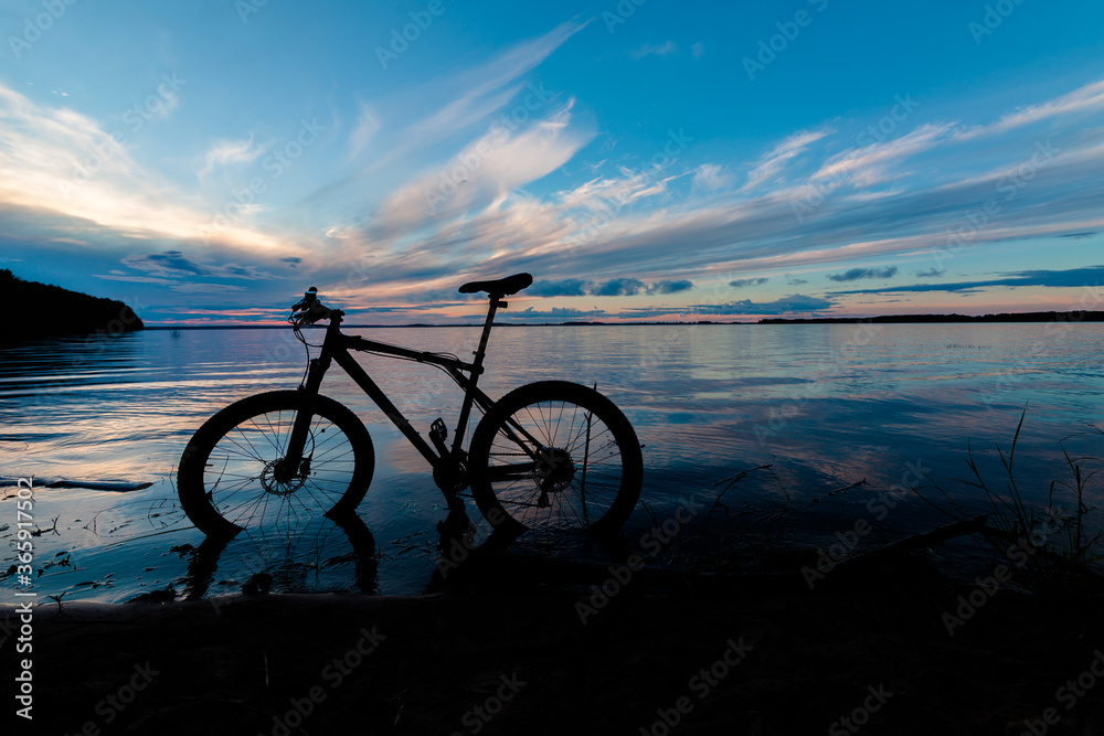 Fototapeta premium evening silhouette of a mountain bike on the lake with a beautiful sunset