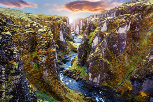 Fantastic view on picturesque canyon Fjadrargljufur with green grass and icelandic moss near river with waterfall. Tipical Icelandic scenery during sunset. Amazing nature landscape during sunset photo