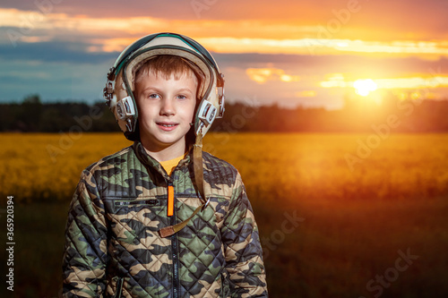 A boy in a pilot's helmet on a sunset background. Dream concept, choice of profession, game. Copy space. © Aliaksandr Marko