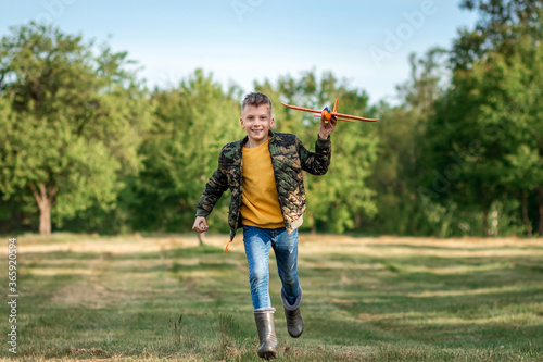 A boy runs across the field and launches a toy airplane against the backdrop of greenery. The concept of dreams, choice of profession, pilot, childhood. Copy space.