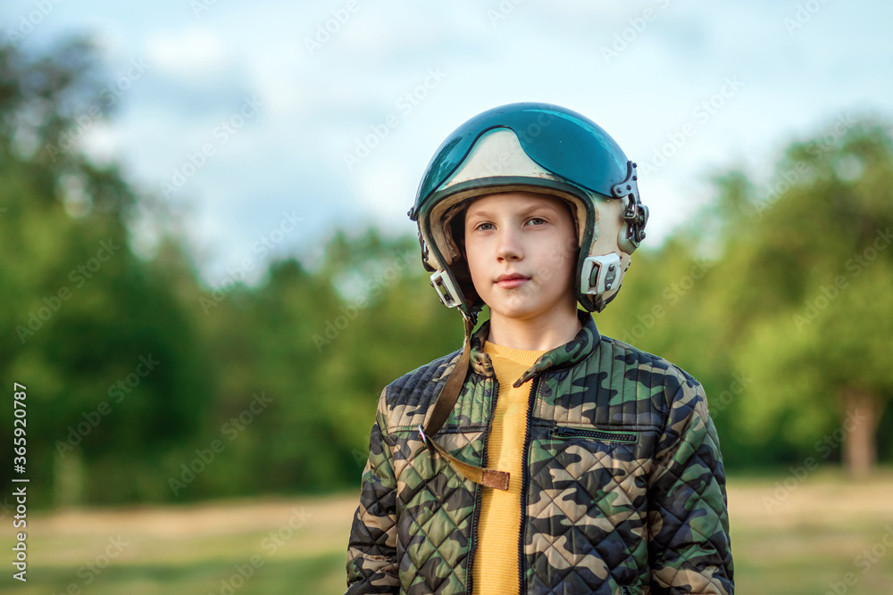 A boy in a pilot's helmet on a background of greenery. Dream concept, choice of profession, game. Copy space. A boy in a pilot's helmet on a background of greenery. Dream concept, choice of profession, game. Copy space.