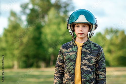A boy in a pilot's helmet on a background of greenery. Dream concept, choice of profession, game. Copy space. © Aliaksandr Marko