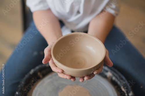 Cuts of product with wire. Craftsman hands making pottery bowl. Woman working on potter wheel. Family business shop sculpts pot from clay.