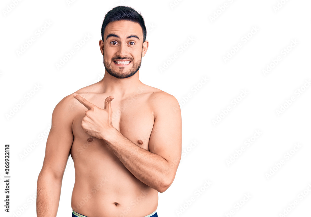 Young handsome man wearing swimwear cheerful with a smile on face pointing with hand and finger up to the side with happy and natural expression