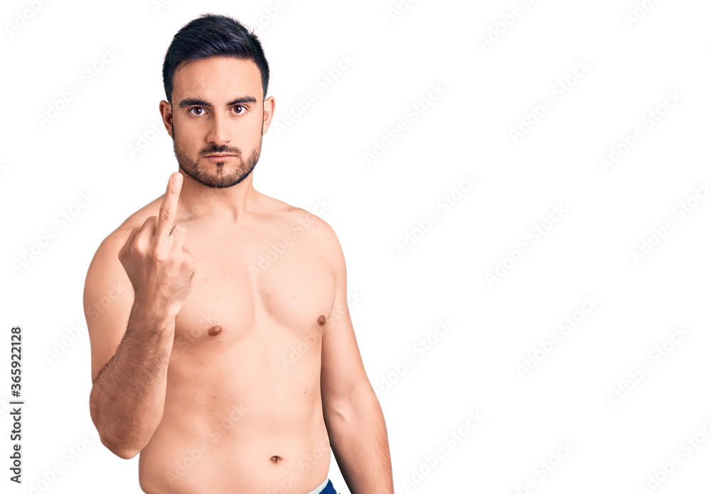 Young handsome man wearing swimwear showing middle finger, impolite and rude fuck off expression Young handsome man wearing swimwear showing middle finger, impolite and rude fuck off expression