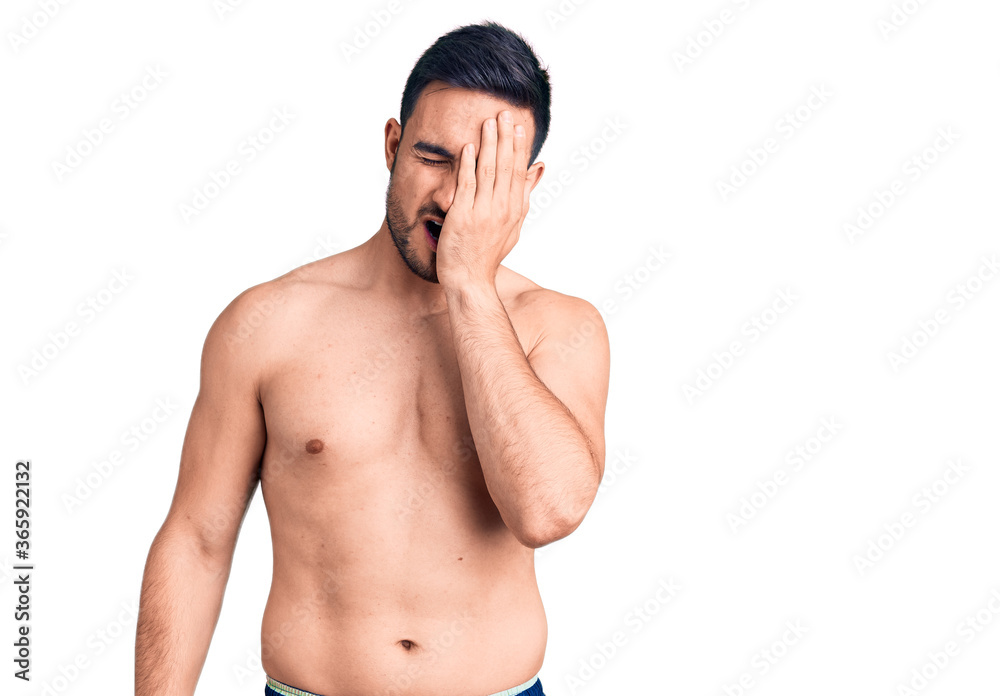 Fototapeta premium Young handsome man wearing swimwear yawning tired covering half face, eye and mouth with hand. face hurts in pain.