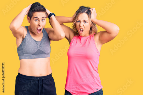 Couple of women wearing sportswear crazy and scared with hands on head, afraid and surprised of shock with open mouth