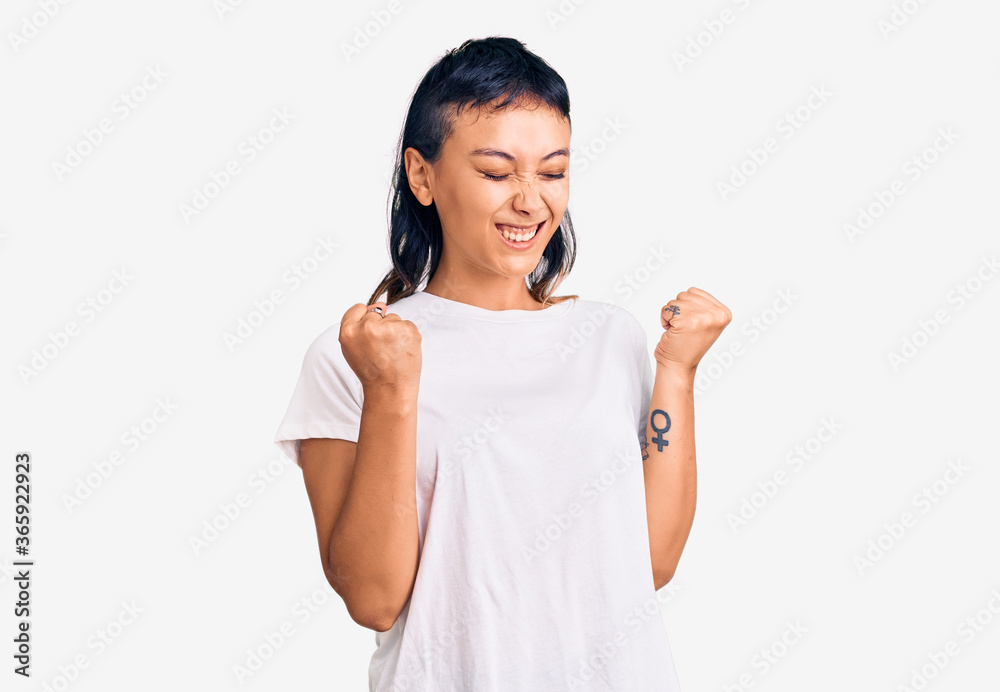 Young woman wearing casual clothes excited for success with arms raised and eyes closed celebrating victory smiling. winner concept. Young woman wearing casual clothes excited for success with arms raised and eyes closed celebrating victory smiling. winner concept.