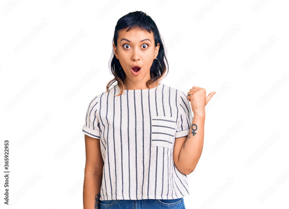 Young woman wearing casual clothes surprised pointing with hand finger to the side, open mouth amazed expression. Young woman wearing casual clothes surprised pointing with hand finger to the side, open mouth amazed expression.