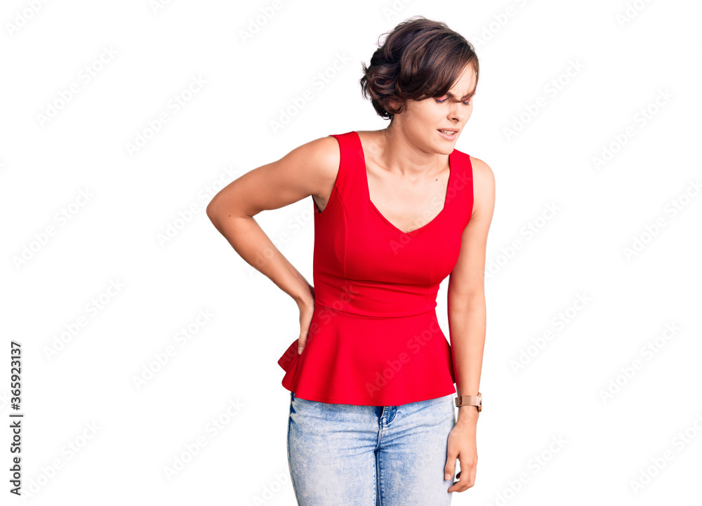 Beautiful young woman with short hair wearing casual style with sleeveless shirt suffering of backache, touching back with hand, muscular pain Beautiful young woman with short hair wearing casual style with sleeveless shirt suffering of backache, touching back with hand, muscular pain