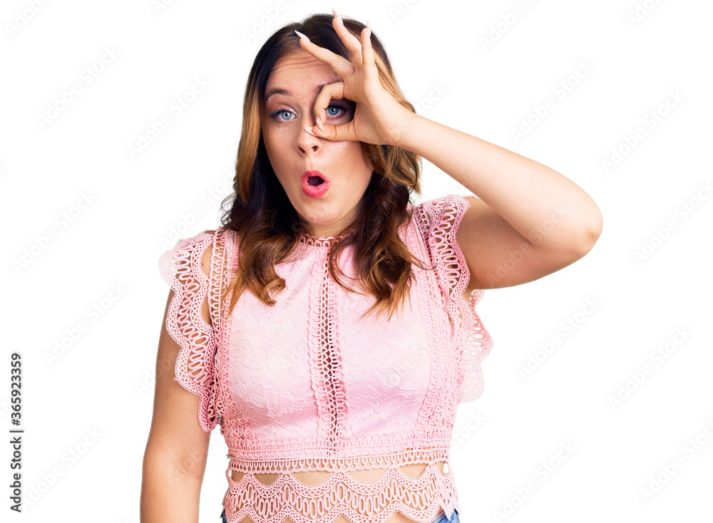Young beautiful caucasian woman wearing casual clothes doing ok gesture shocked with surprised face, eye looking through fingers. unbelieving expression.
