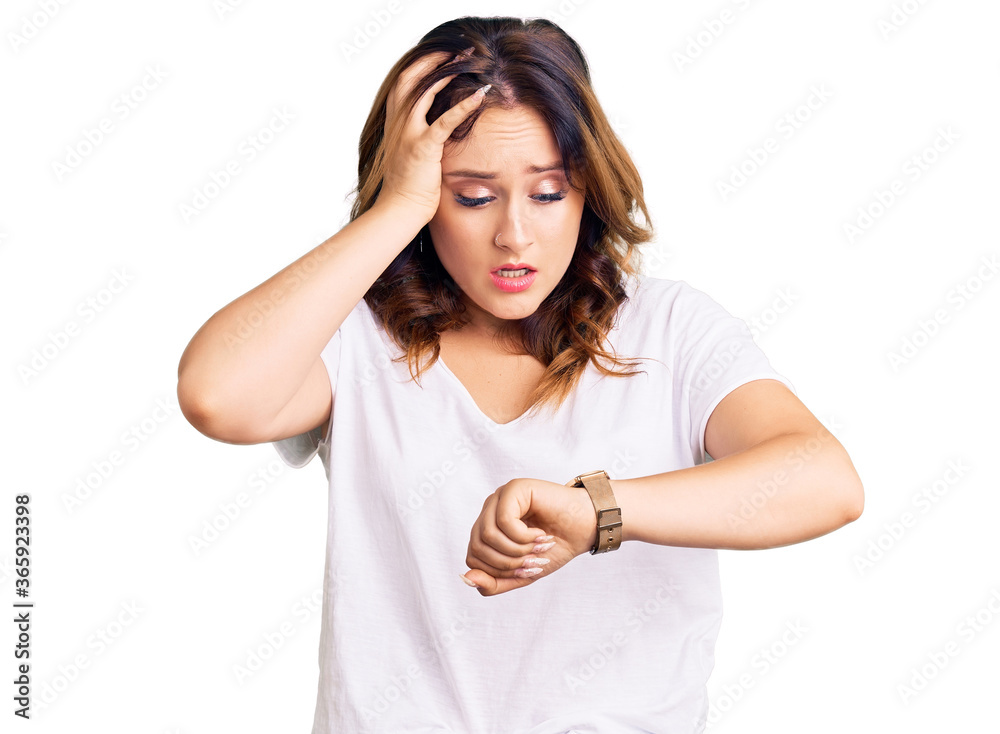 Young beautiful caucasian woman wearing casual white tshirt looking at the watch time worried, afraid of getting late Young beautiful caucasian woman wearing casual white tshirt looking at the watch time worried, afraid of getting late