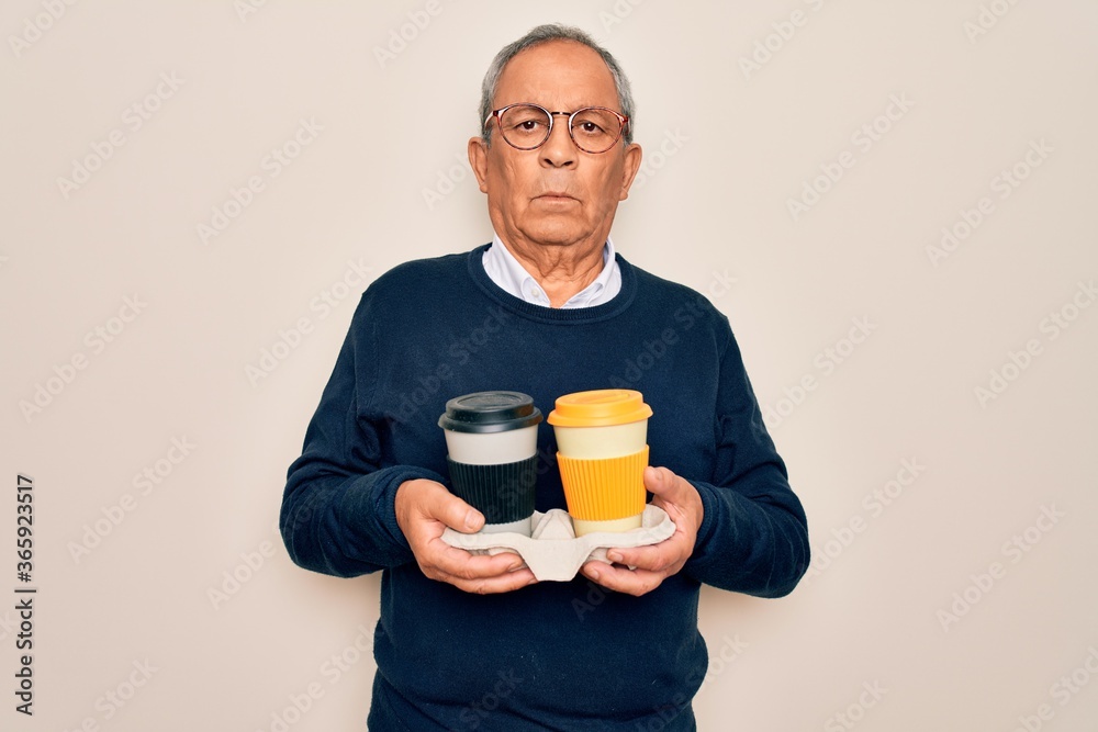 Senior handsome hoary man holding tray with takeaway cups of coffee over white background with a confident expression on smart face thinking serious Senior handsome hoary man holding tray with takeaway cups of coffee over white background with a confident expression on smart face thinking serious
