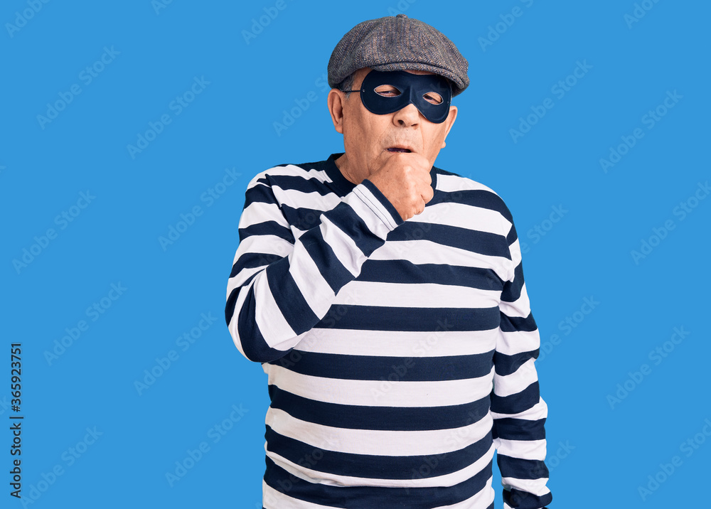 Senior handsome man wearing burglar mask and t-shirt feeling unwell and coughing as symptom for cold or bronchitis. health care concept. Senior handsome man wearing burglar mask and t-shirt feeling unwell and coughing as symptom for cold or bronchitis. health care concept.