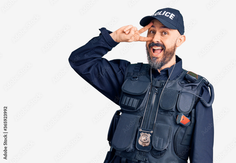 Young handsome man wearing police uniform doing peace symbol with fingers over face, smiling cheerful showing victory