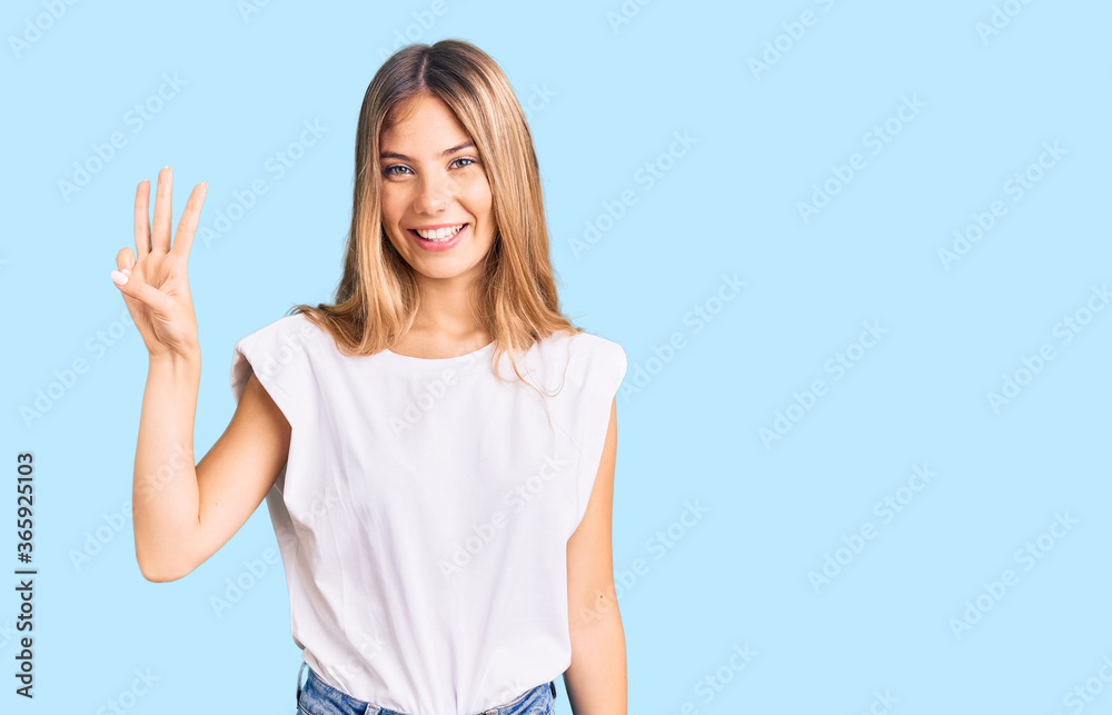 Fototapeta premium Beautiful caucasian woman with blonde hair wearing casual white tshirt showing and pointing up with fingers number three while smiling confident and happy.