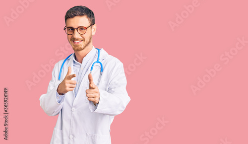 Handsome young man with bear wearing doctor uniform pointing fingers to camera with happy and funny face. good energy and vibes.