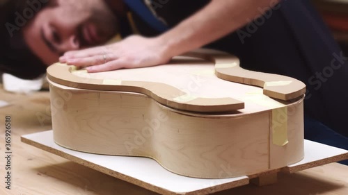 Young artisan making classical guitar in the workshop, time-lapse of guitar making