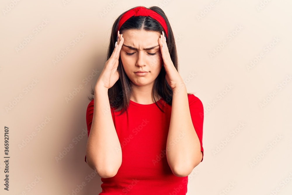 Young beautiful girl wearing casual t shirt and diadem with hand on head for pain in head because stress. suffering migraine. Young beautiful girl wearing casual t shirt and diadem with hand on head for pain in head because stress. suffering migraine.