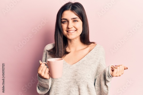 Young beautiful girl drinking mug of coffee screaming proud, celebrating victory and success very excited with raised arm
