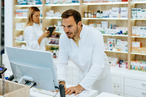 Male and female pharmacists working together at modern pharmacy.