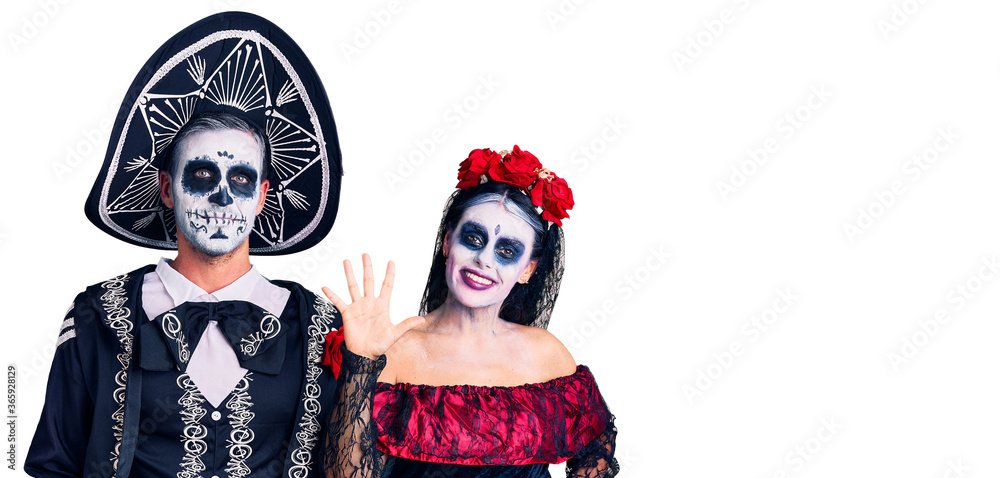 Young couple wearing mexican day of the dead costume over background showing and pointing up with fingers number five while smiling confident and happy.
