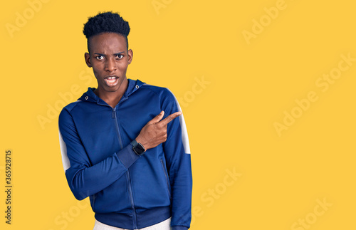 Young african american man wearing sportswear pointing aside worried and nervous with forefinger, concerned and surprised expression © Krakenimages.com