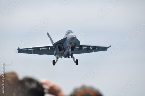 Fighter jet descending to land on aircraft carrier