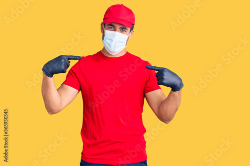 Young hispanic man wearing covid-19 safety mask looking confident with smile on face, pointing oneself with fingers proud and happy.