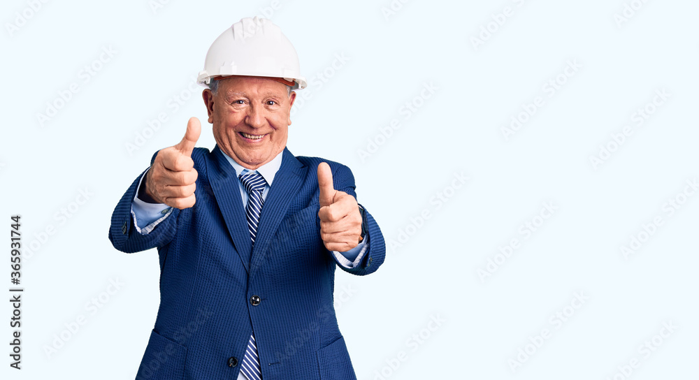 Senior handsome grey-haired man wearing suit and architect hardhat approving doing positive gesture with hand, thumbs up smiling and happy for success. winner gesture. Senior handsome grey-haired man wearing suit and architect hardhat approving doing positive gesture with hand, thumbs up smiling and happy for success. winner gesture.