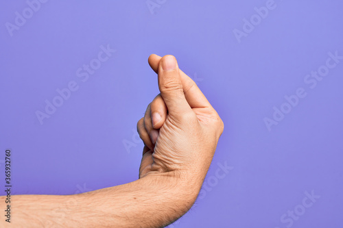 Hand of caucasian young man showing fingers over isolated purple background holding blank space with thumb finger  business and advertising