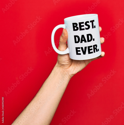 Beautiful hand of man holding cup of coffee with best dad ever message over isolated red background photo