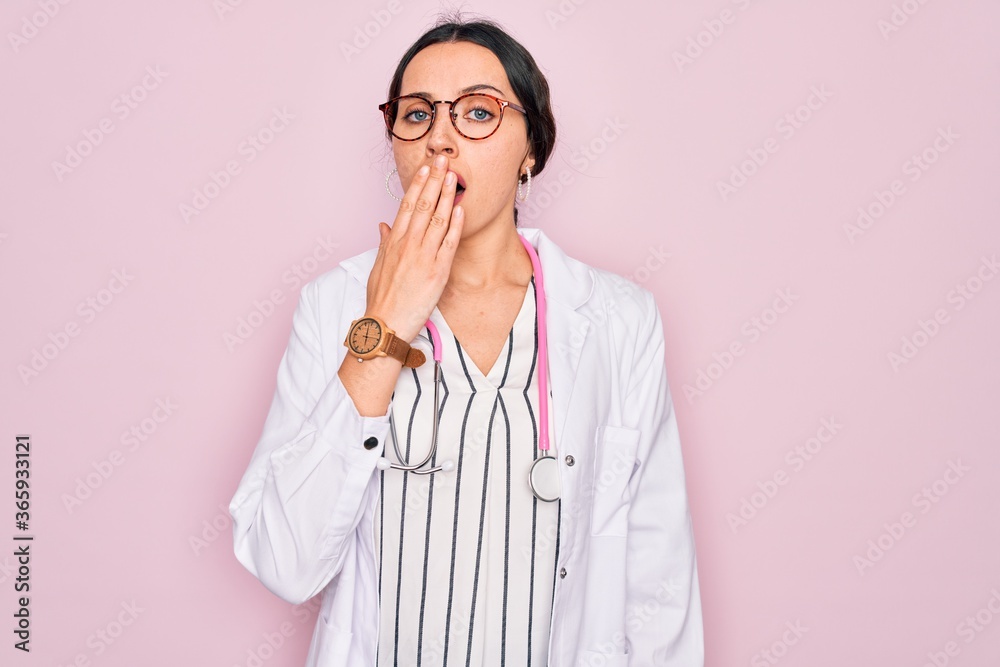 Beautiful doctor woman with blue eyes wearing coat and stethoscope over pink background bored yawning tired covering mouth with hand. Restless and sleepiness. Beautiful doctor woman with blue eyes wearing coat and stethoscope over pink background bored yawning tired covering mouth with hand. Restless and sleepiness.