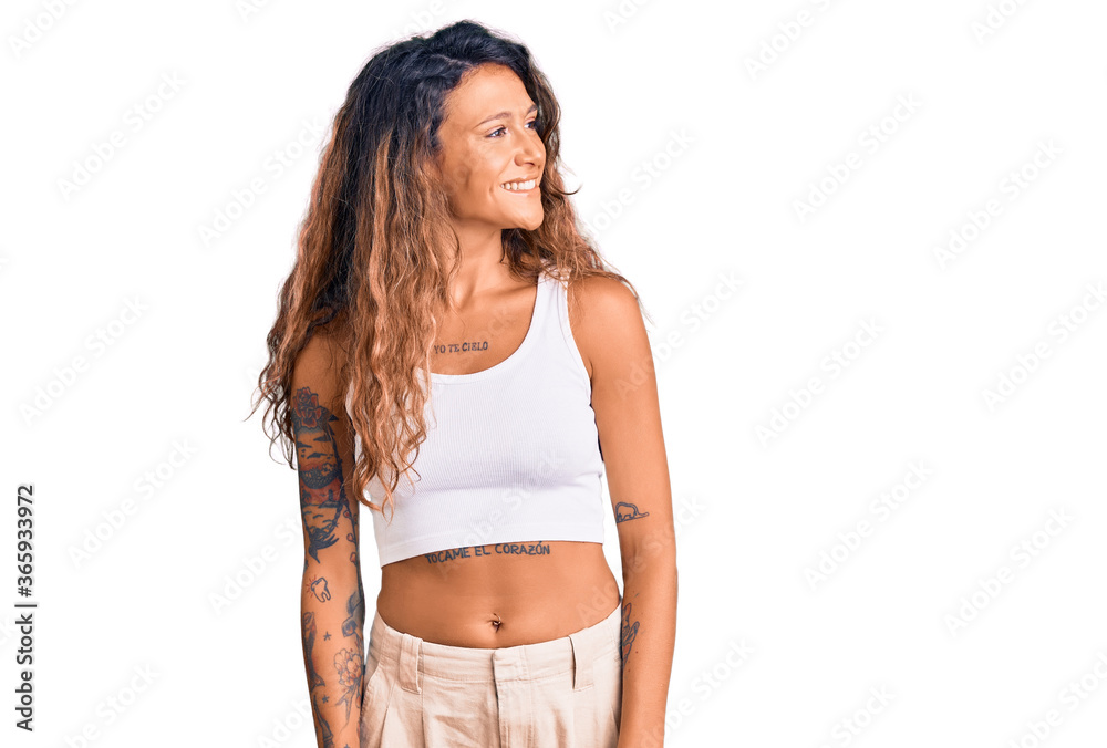 Young hispanic woman with tattoo wearing casual clothes looking away to side with smile on face, natural expression. laughing confident. Young hispanic woman with tattoo wearing casual clothes looking away to side with smile on face, natural expression. laughing confident.