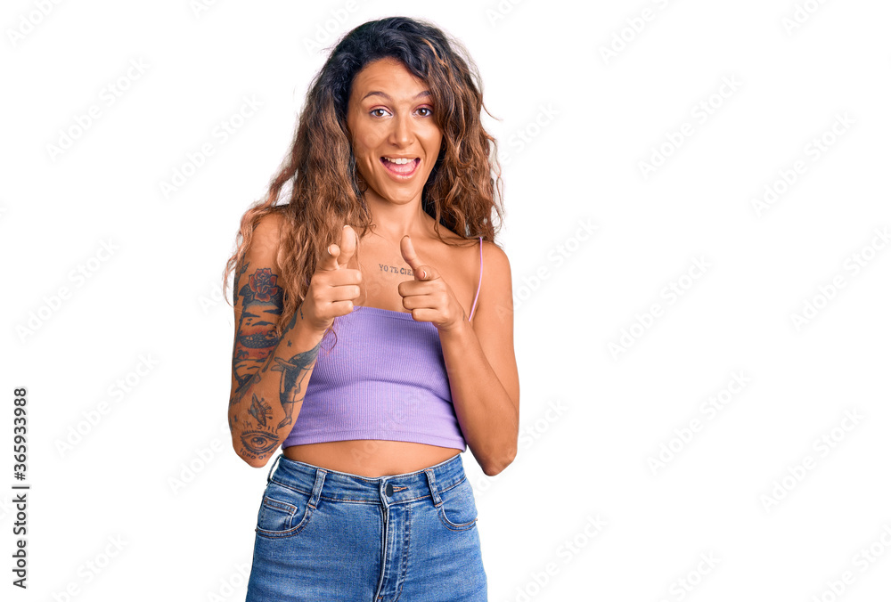 Young hispanic woman with tattoo wearing casual clothes pointing fingers to camera with happy and funny face. good energy and vibes. Young hispanic woman with tattoo wearing casual clothes pointing fingers to camera with happy and funny face. good energy and vibes.