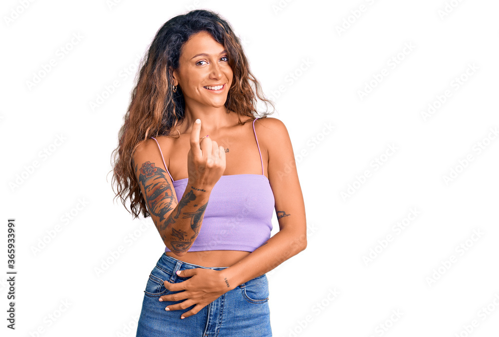Young hispanic woman with tattoo wearing casual clothes beckoning come here gesture with hand inviting welcoming happy and smiling Young hispanic woman with tattoo wearing casual clothes beckoning come here gesture with hand inviting welcoming happy and smiling