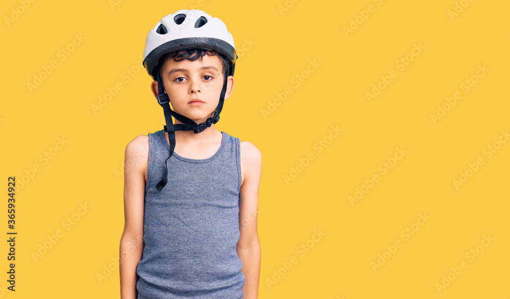 Little cute boy kid wearing bike helmet with serious expression on face. simple and natural looking at the camera.