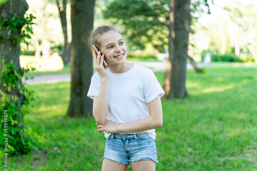 The little girl is emotionally talking on her cell phone. The park, the trees.