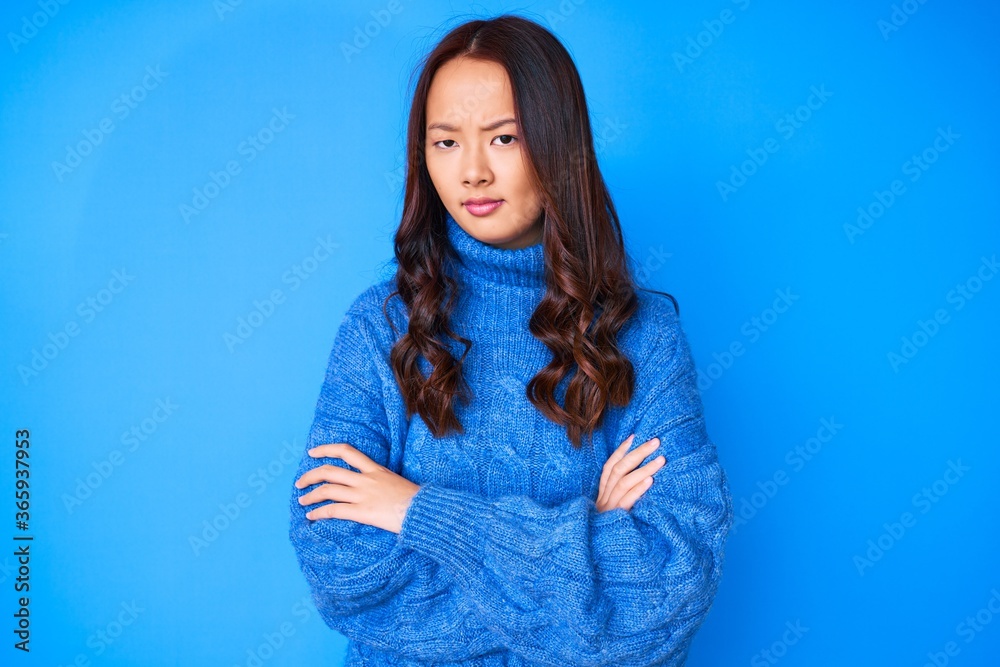 Young beautiful chinese girl wearing casual winter sweater skeptic and nervous, disapproving expression on face with crossed arms. negative person.