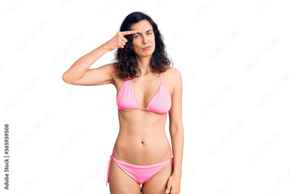 Fototapeta premium Young beautiful hispanic woman wearing bikini pointing unhappy to pimple on forehead, ugly infection of blackhead. acne and skin problem