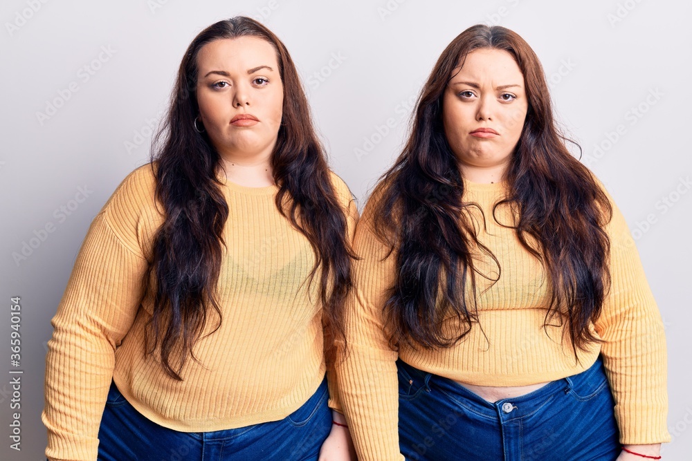 Young plus size twins wearing casual clothes depressed and worry for distress, crying angry and afraid. sad expression. Young plus size twins wearing casual clothes depressed and worry for distress, crying angry and afraid. sad expression.