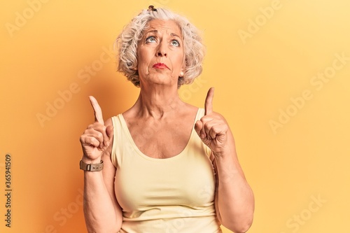 Senior grey-haired woman wearing casual clothes pointing up looking sad and upset, indicating direction with fingers, unhappy and depressed. photo