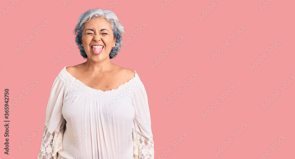 Senior woman with gray hair wearing bohemian style sticking tongue out happy with funny expression. emotion concept.