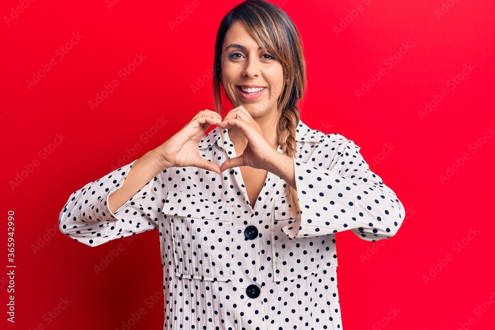 Young beautiful woman wearing casual dress smiling in love doing heart symbol shape with hands. romantic concept.