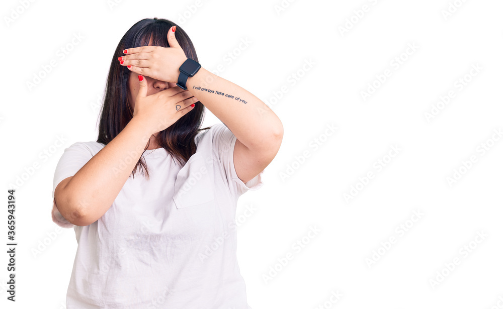 Young plus size woman wearing casual clothes covering eyes and mouth with hands, surprised and shocked. hiding emotion Young plus size woman wearing casual clothes covering eyes and mouth with hands, surprised and shocked. hiding emotion